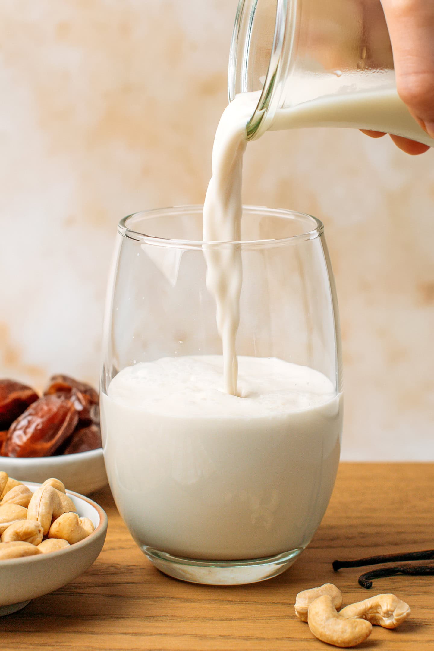 Pouring fresh cashew milk into a glass.