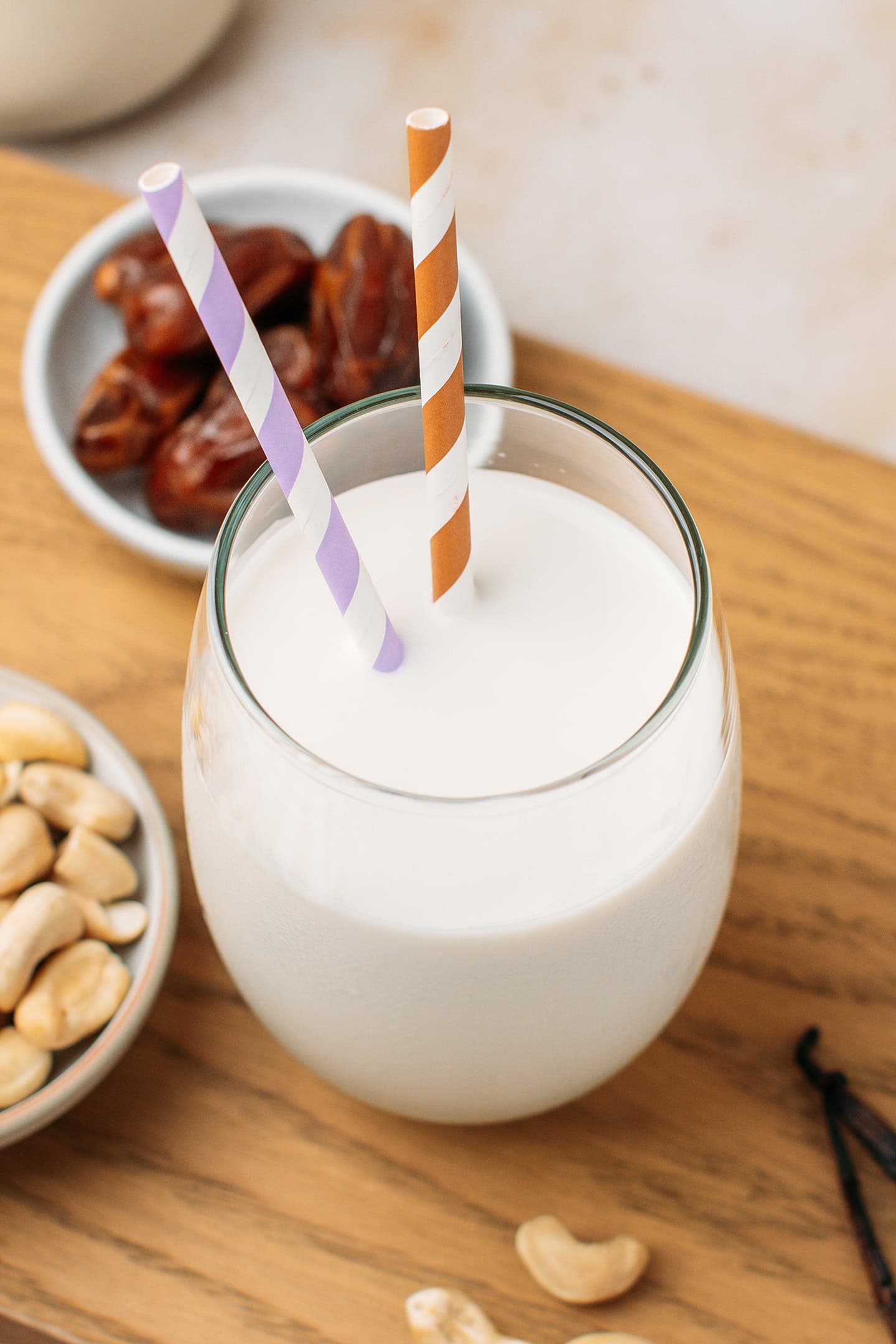 Glass of cashew milk with colorful straws.