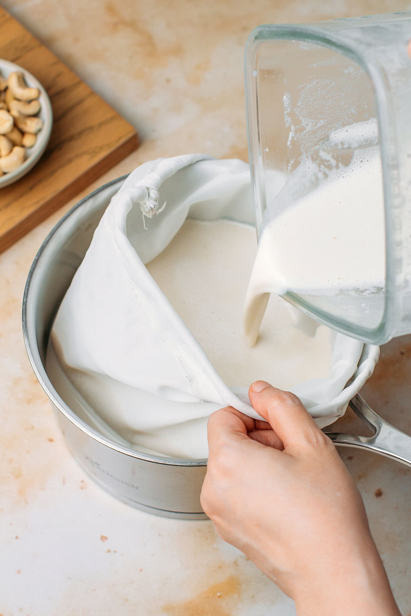 Pouring cashew milk into a nut milk bag.