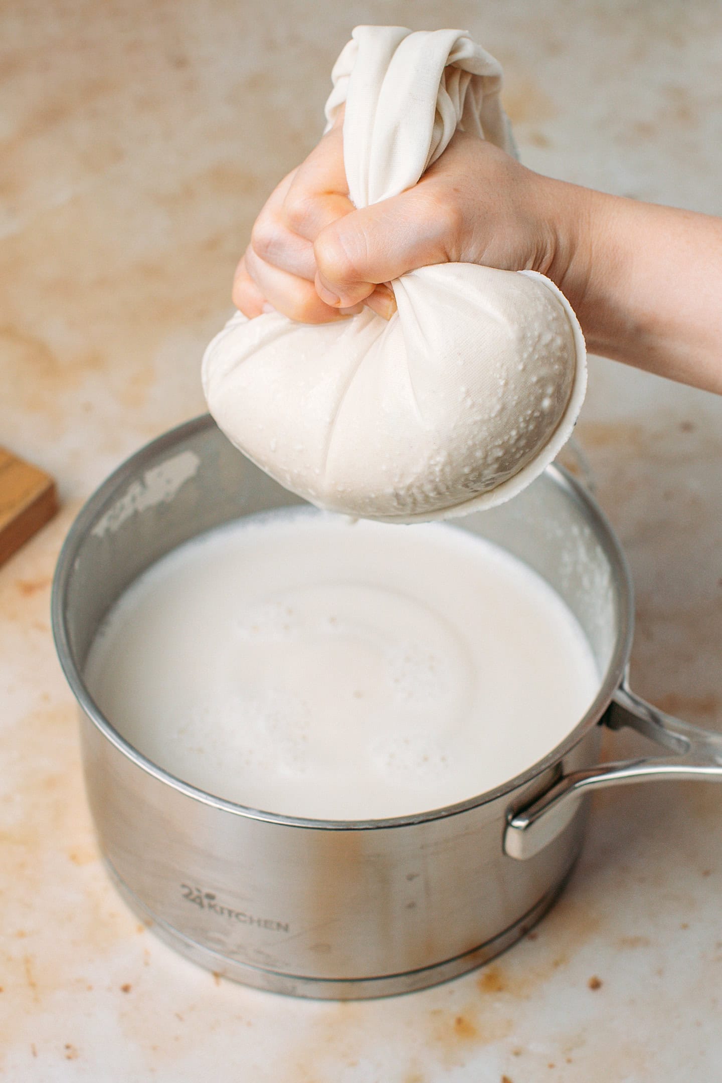 Squeezing a nut milk bag over a pot.