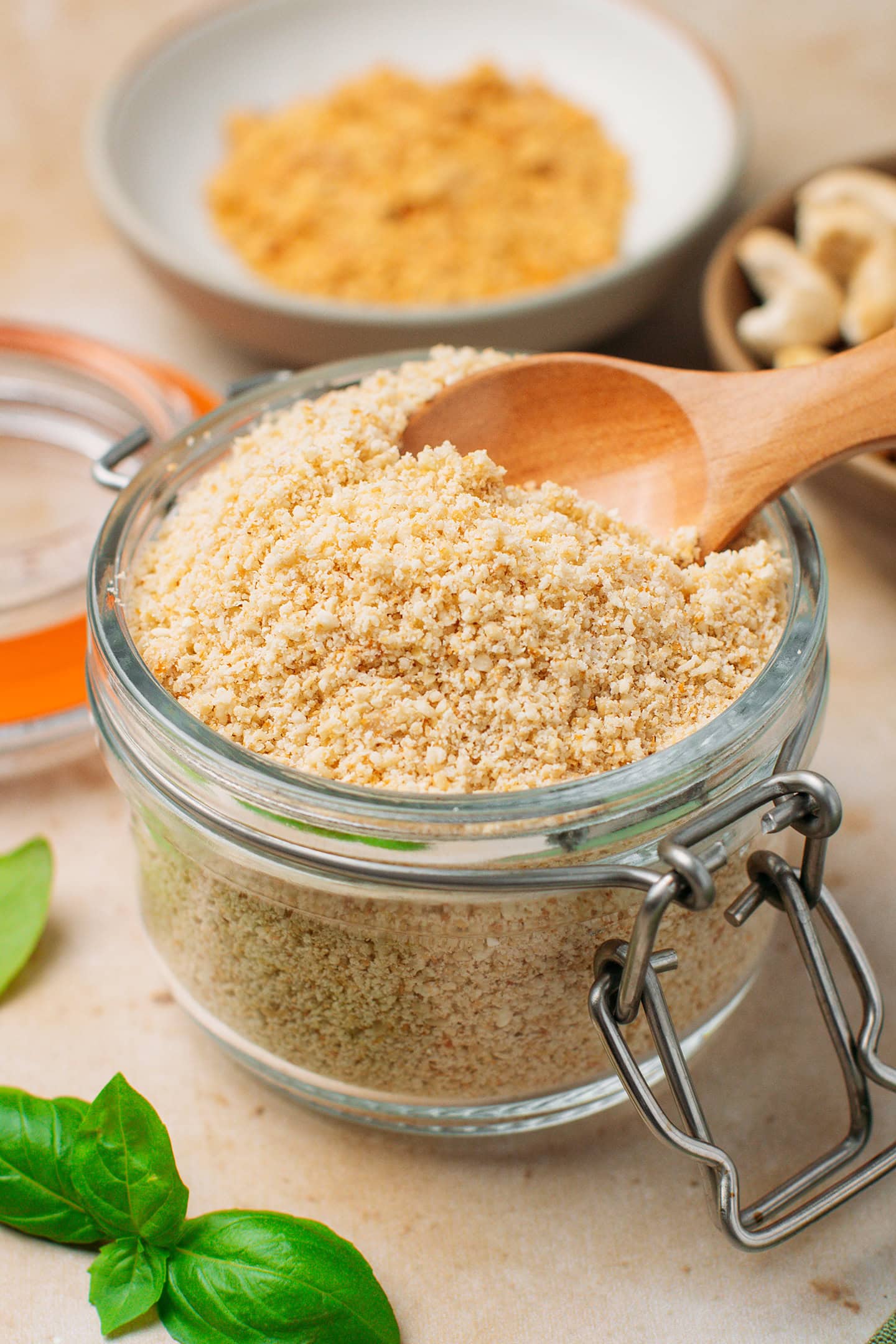 Jar of vegan parmesan with a small wooden spoon inside.