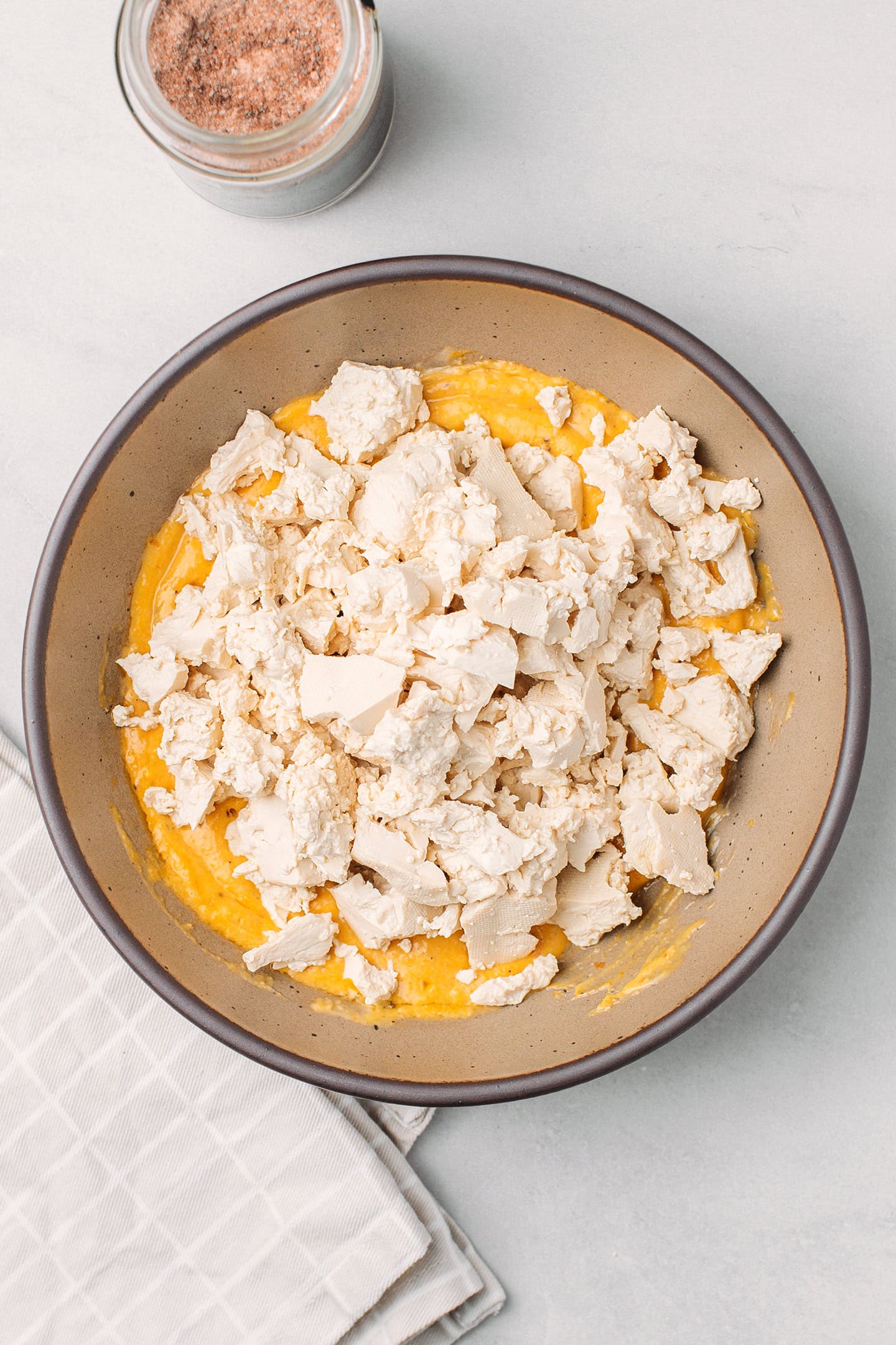 Mayo and pumpkin sauce with crumbled tofu in a bowl.
