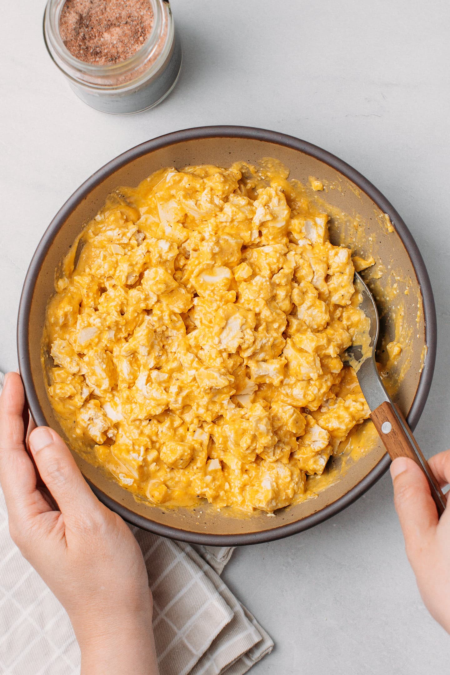 Mixing crumbled tofu with a mayo-based sauce in a bowl.