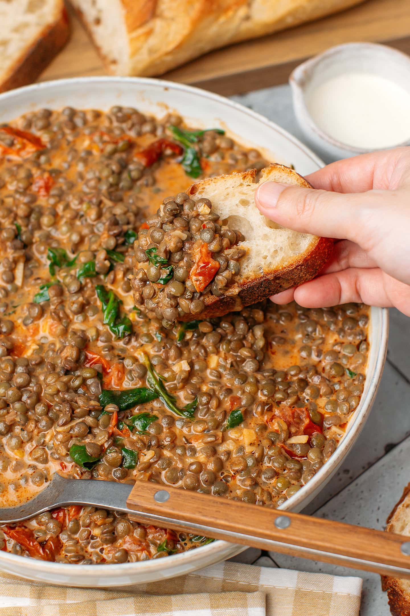 Dipping a slice of bread into a bowl of saucy lentils.