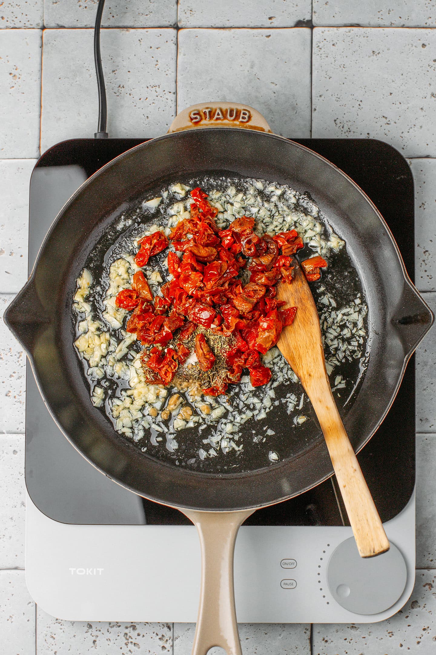Sautéed garlic and chopped sun-dried tomatoes in a skillet.