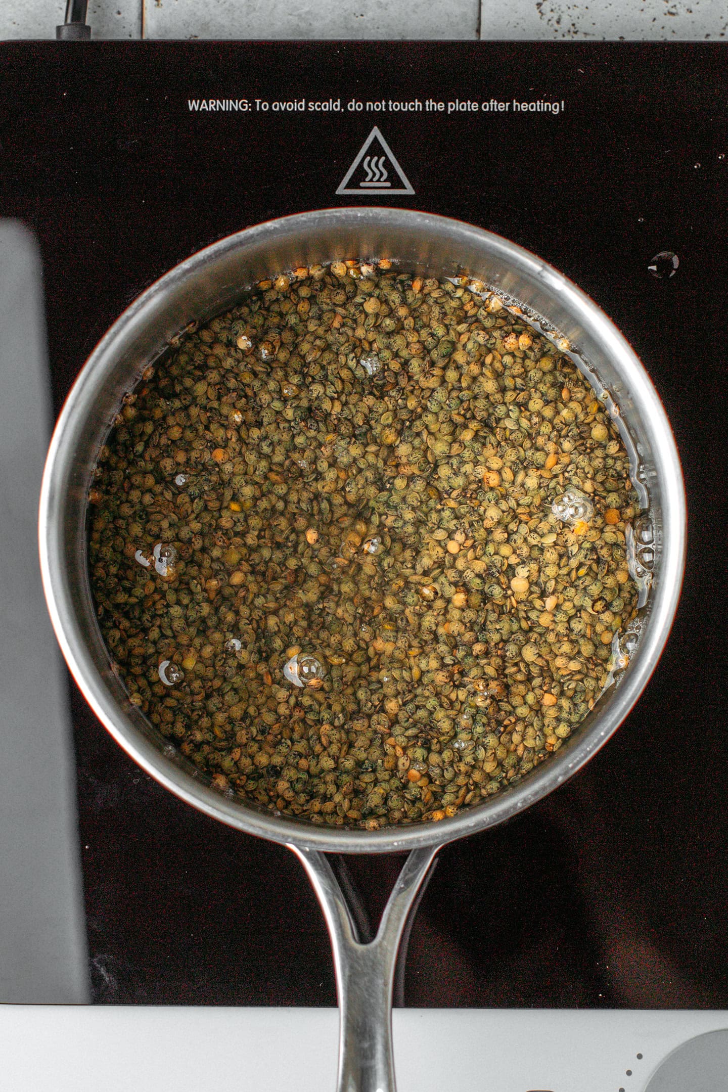 Green lentils and water in a saucepan.