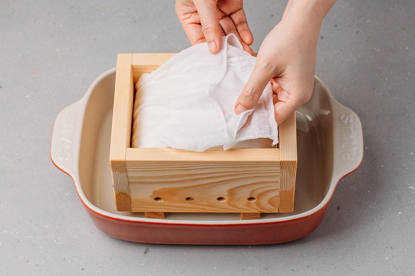 Folding a cheesecloth over the curds.