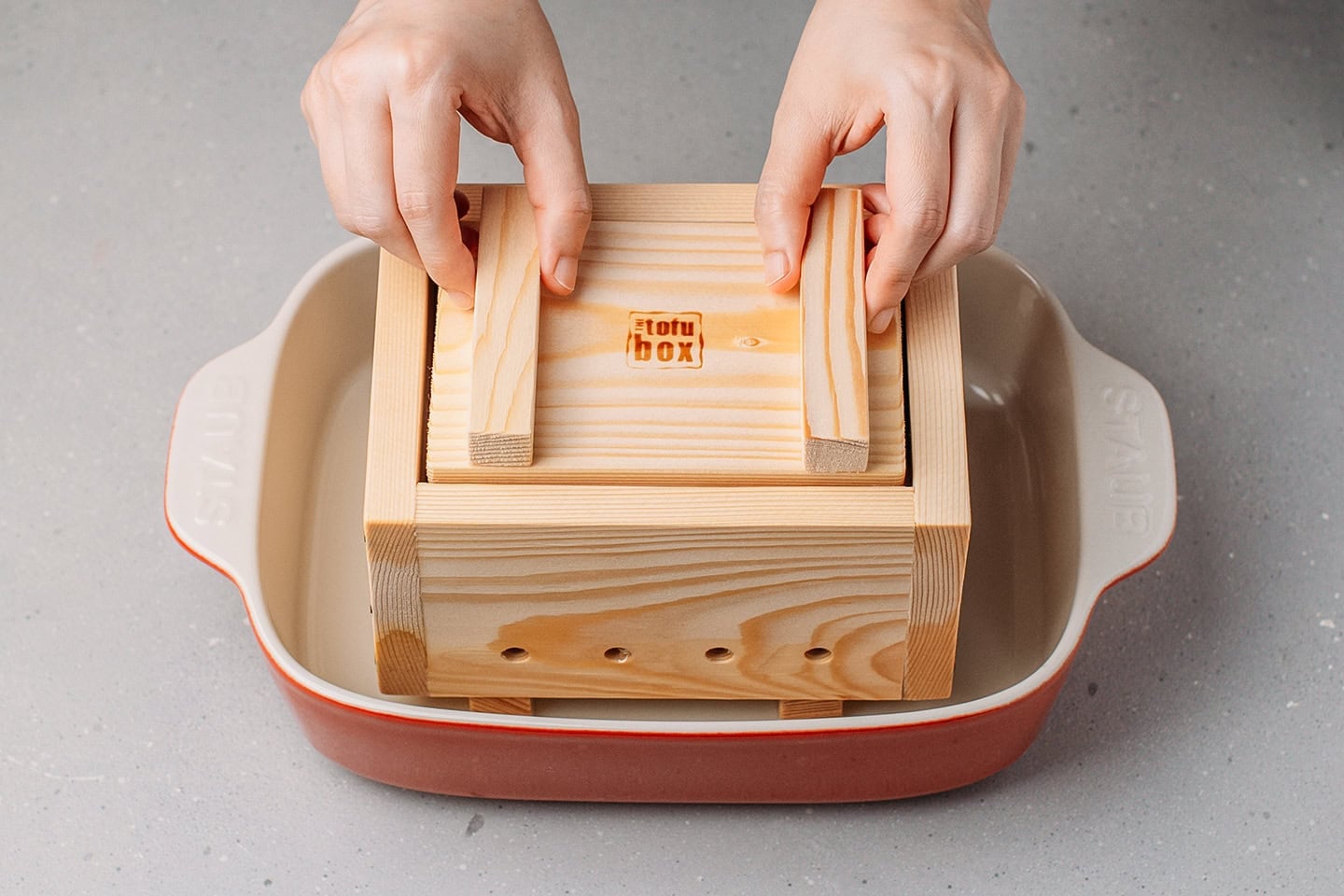 Placing the tofu press lid on top of the curds.