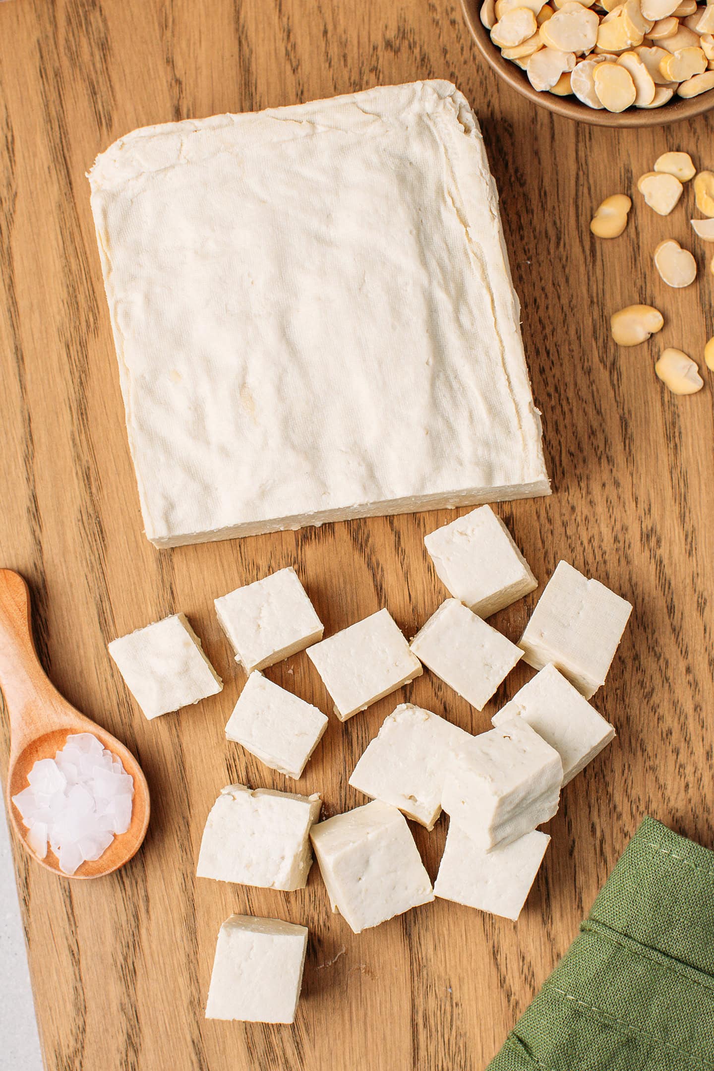 Loaf and cubes of fava bean tofu on a wooden board.