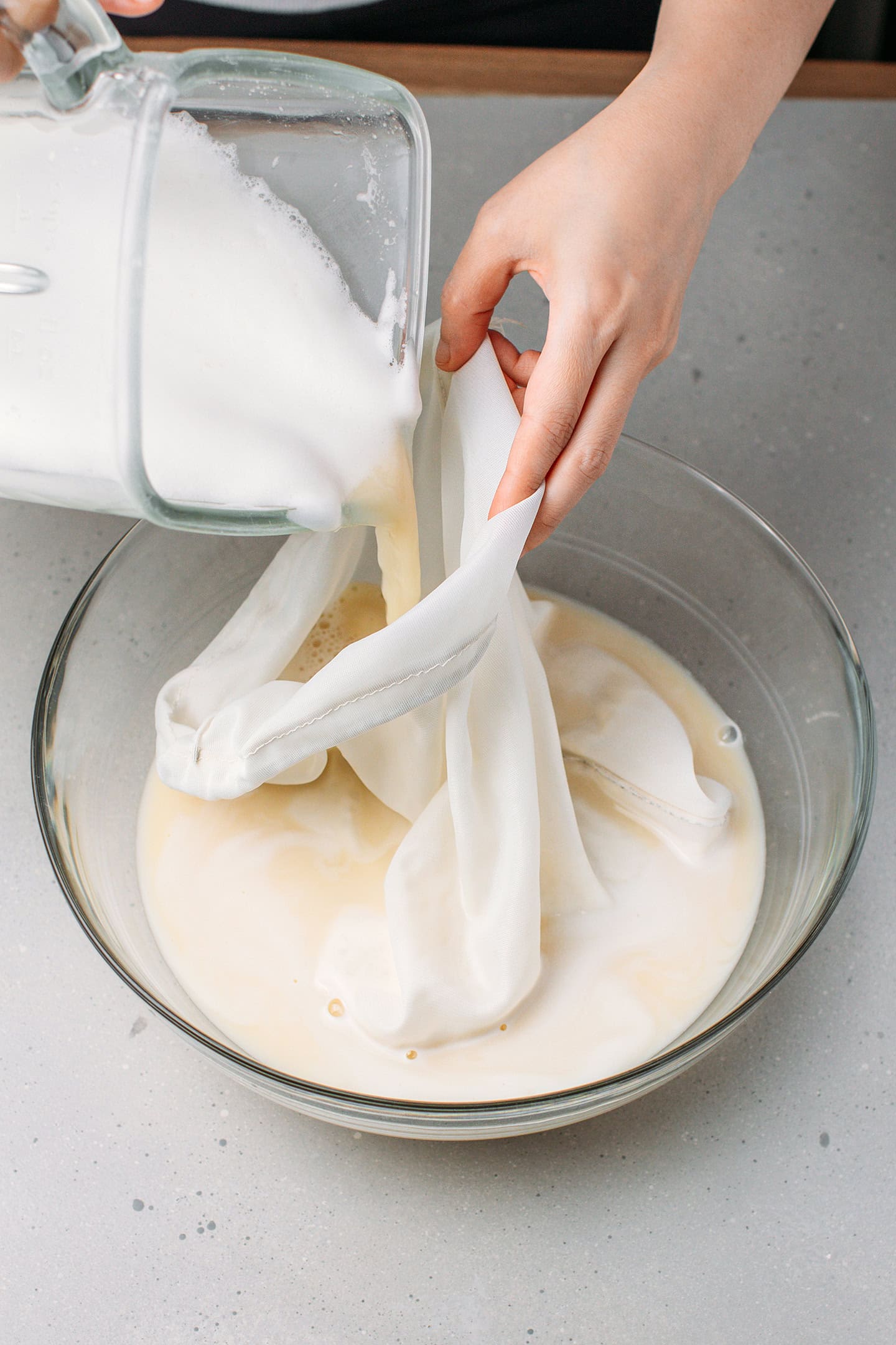 Pouring fava bean mixture into a nut milk bag.