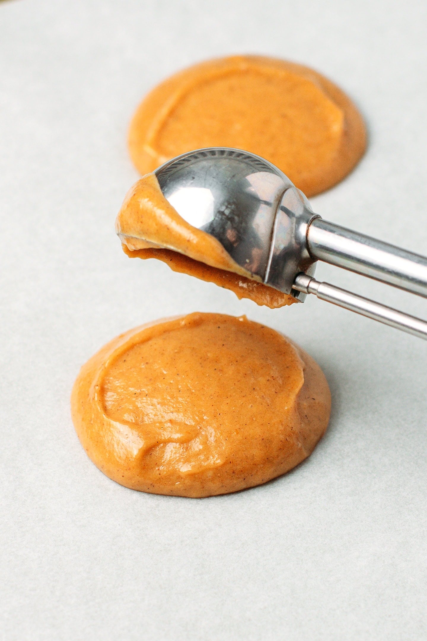 Dropping pumpkin batter rounds on a baking sheet.