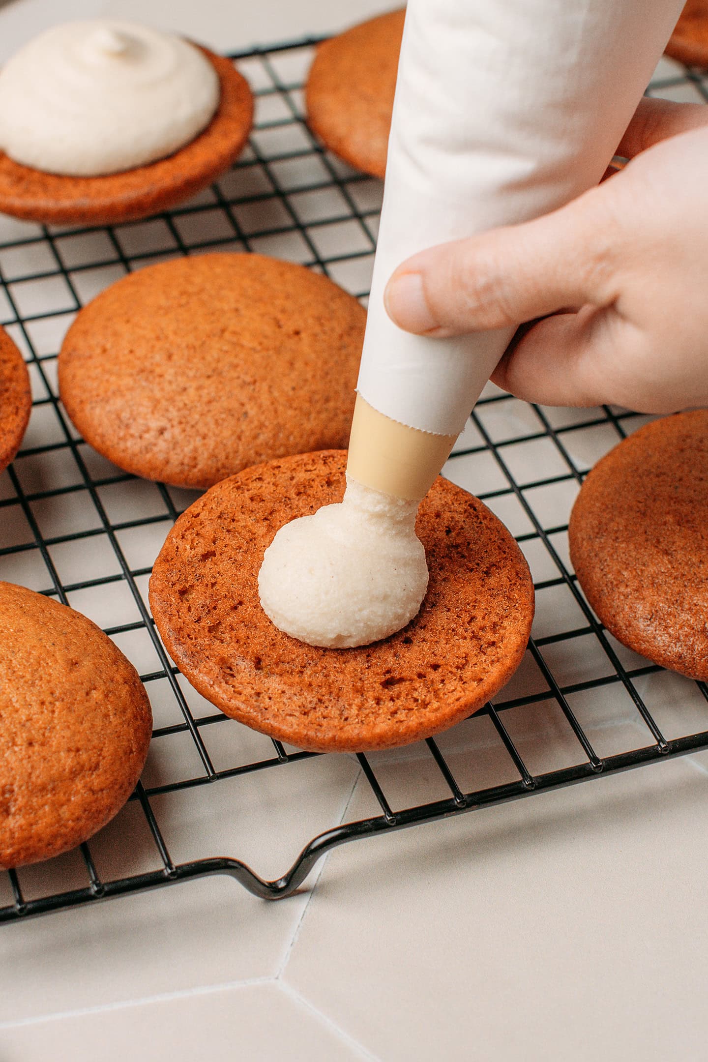 Piping cashew cream onto a pumpkin cake.