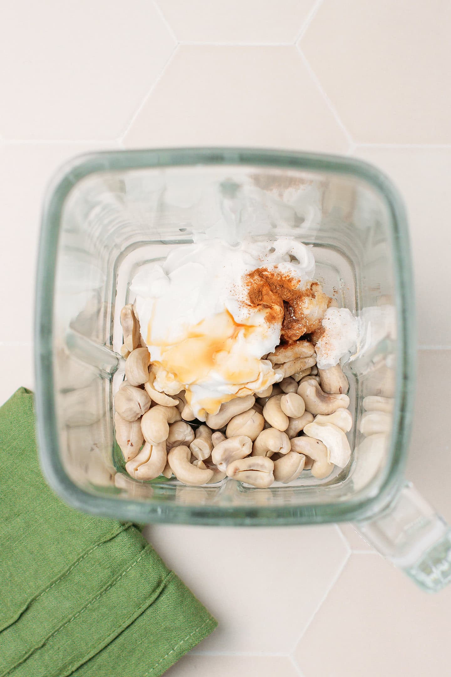 Raw cashews, coconut cream, powdered sugar, and vanilla extract in a blender.