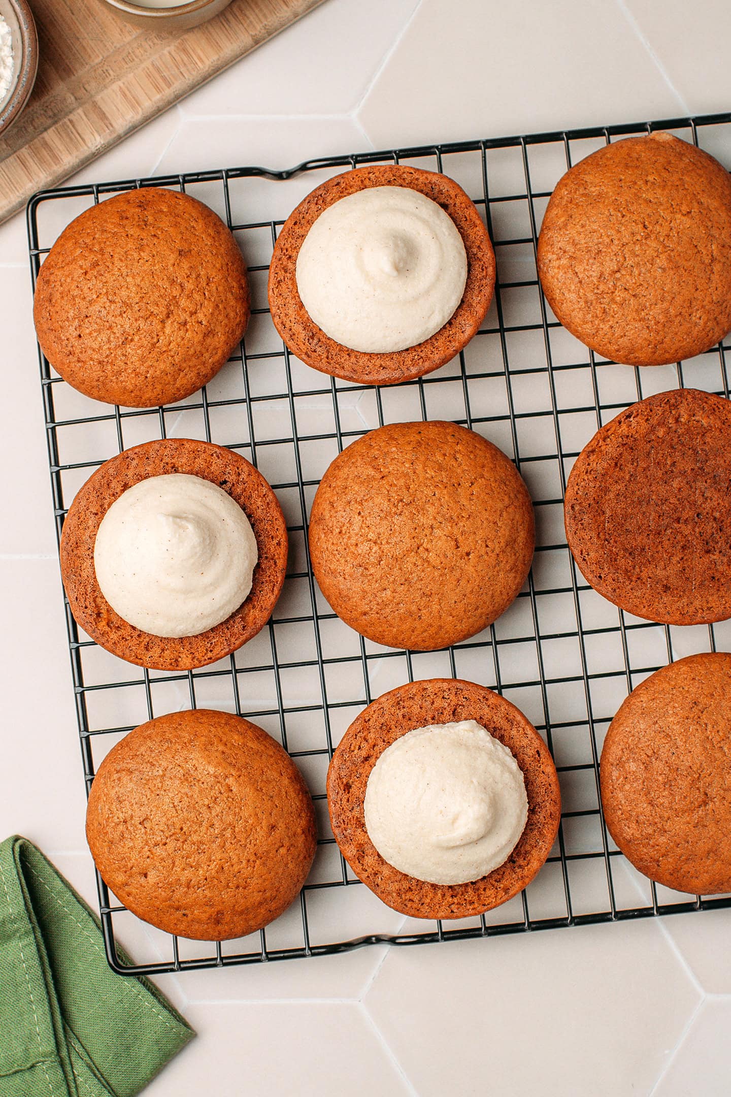 Pumpkin cookies filled with cashew cream on a cooling rack.