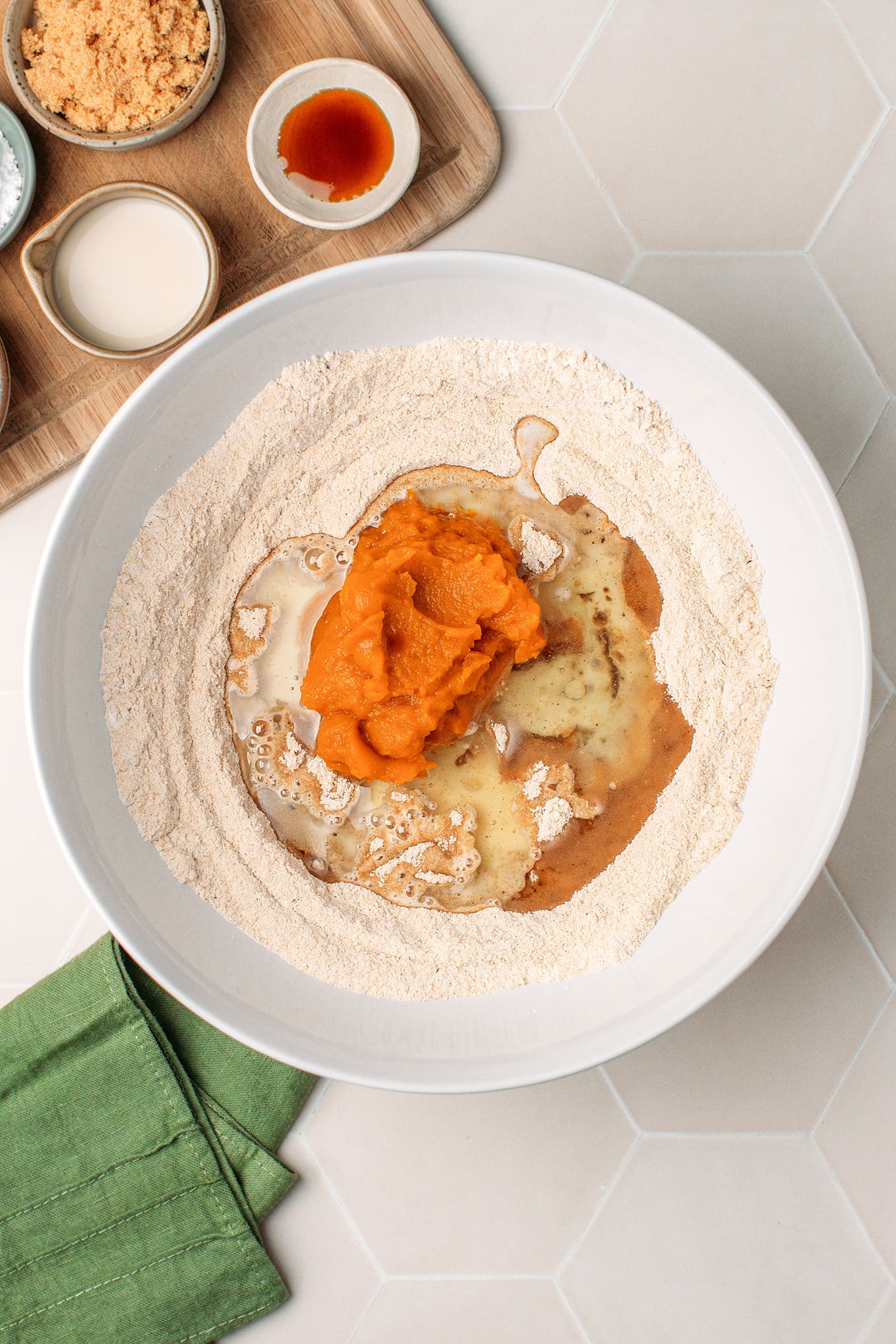 Flour, sugar, pumpkin purée, oil, and milk in a mixing bowl.